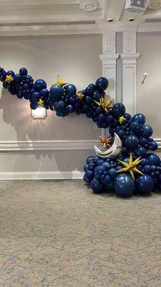 an arch made out of balloons with stars and moon on it in the middle of a room