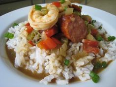 a white plate topped with rice covered in meat and veggies on top of it