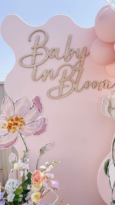 there is a sign that says baby in bloom on the side of a pink wall