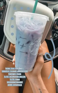 a woman is holding a starbucks drink in her hand while sitting in the backseat of a car