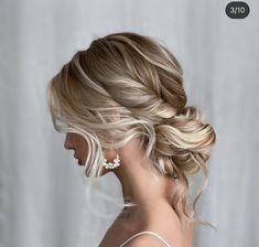 a woman with blonde hair in a low updo and earrings on her head is looking back