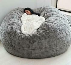 a woman laying on top of a bean bag chair in the middle of a room