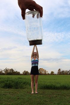 a woman is holding up a jar in the air with her hands above her head