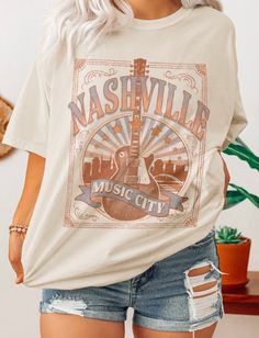 Description- -Oversized Graphic Tee Shirt -Nashville Music City Graphic -Crewneck Size Chart Small Medium Large Bust 34 36 38 Waist 26 28 30 High Hip 34 36 38 Low Hip 37 39 41 **in inches** Our crewneck Music City graphic tee shirt fits slightly oversized and features a bold fun graphic. We love this style paired with our Kristin stripped flared pants. You can take this oversized tee and mix it up with a skirt or a pair of jean shorts. This is a great basic to spice up your Spring/Summer wardrob Soft-washed Tops For Fall Concert, Soft-washed Tops For Spring Concert, Graphic Tee For Spring Country Concerts, Soft-washed T-shirt For Concerts In Fall, Soft-washed T-shirt For Fall Concerts, Fall Graphic Tee For Country Concerts, Fall Letter Print T-shirt For Country Concerts, Spring Crew Neck T-shirt For Country Concerts, Trendy Crew Neck Tops For Country Concerts