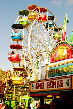 an amusement park ride with colorful rides and people standing around it on a sunny day