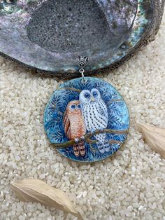 two owls sitting on a tree branch in front of a blue and white plate with feathers