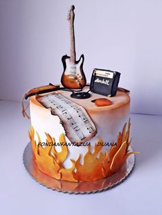 a cake decorated with music instruments and fire on it's sides, including an electric guitar