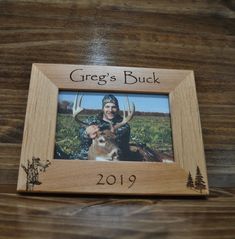 a wooden frame with an image of a woman and a deer on it that says greg's buck