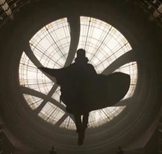 the silhouette of a person standing in front of a circular window