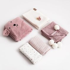 four pieces of baby's clothing and accessories laid out on a white table top