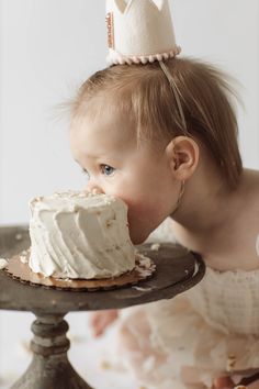 a baby girl eating a cake with a crown on top of it's head