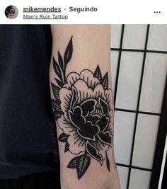 a black and white flower tattoo on the left arm, with leaves around it's edges