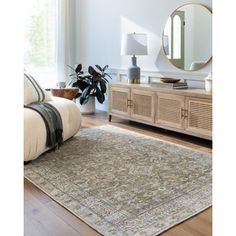 a living room area with a couch, mirror and rug on the floor in front of a window