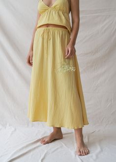 Float through your day in our Mökki Skirt in Sunlight, a pastel yellow that effortlessly captures the essence of summer. Hand-dyed by local artisans, each skirt carries a unique story of craftsmanship and style, ensuring that you wear a piece as one-of-a-kind as you are. This timeless skirt is our favourite for accompanying you from soft mornings to magical evenings. Crafted from the softest Cotton Bubble texture, this simple, classic shape creates the ultimate summer skirt. The flowy, feminine silhouette drapes gracefully, celebrating your natural beauty. An adjustable drawstring and soft elastic waistline ensure a comfortable, custom fit. Effortlessly mix and match through seasonal changes and mood shifts for uncomplicated elegance. Non-see-through fabric provides peace of mind; for opti Bubble Texture, Yoga Flare Pants, Seasonal Changes, Fabric Journals, Feminine Silhouette, Pastel Yellow, Summer Skirts, Knitwear Cardigan, Local Artisans