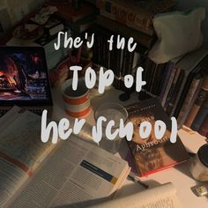 the top of her school is surrounded by books, cups and other items on a desk