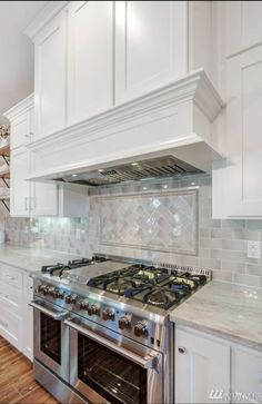 a stove top oven sitting inside of a kitchen next to white cabinets and counter tops