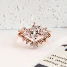 a diamond ring sitting on top of a white table next to a book and magazine