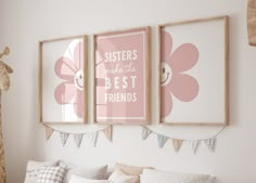 two pink posters hanging on the wall above a white bed with pillows and pillow covers