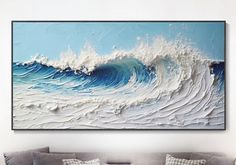 a living room with a couch and large painting on the wall above it that has waves coming in to shore