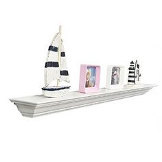 there is a shelf with three pictures and a sailboat on it