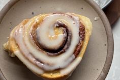 a cinnamon roll sitting on top of a plate next to another pan filled with rolls