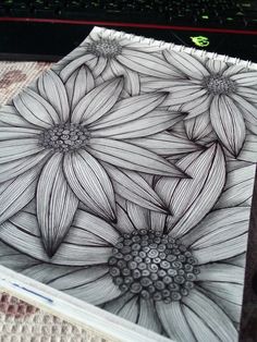 a drawing of some flowers in front of a laptop computer on top of a table