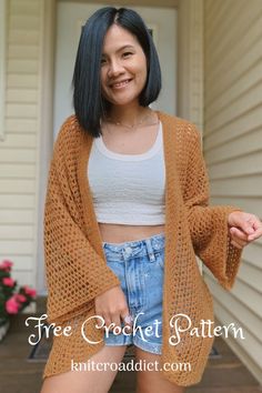 a woman standing in front of a house wearing a brown cardigan sweater and denim shorts