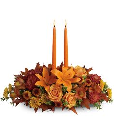 an arrangement of flowers and candles on a white background with the centerpiece in fall colors