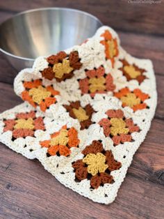 a crocheted dishcloth is sitting on a table next to a metal bowl