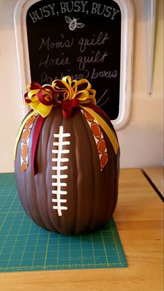 a chocolate pumpkin with a football on it sitting on a cutting board next to a chalkboard