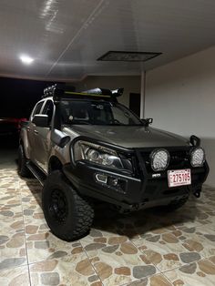 a black truck parked in a garage next to a red and white car with its lights on