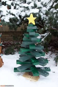 a christmas tree made out of wooden blocks in the snow with a star on top