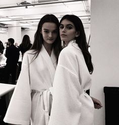 two women standing next to each other in bathrobes and posing for the camera