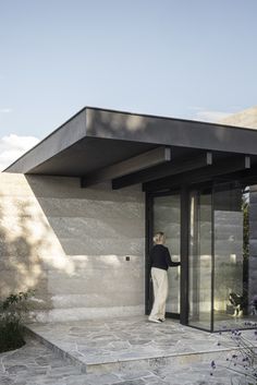 a woman is standing at the entrance to a house with glass doors and stone steps