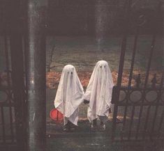 two ghostly people standing in front of a gate