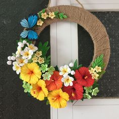 a wreath with flowers and butterflies is hanging on the front door to decorate it for someone's special occasion