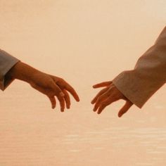 two hands reaching out towards each other over water