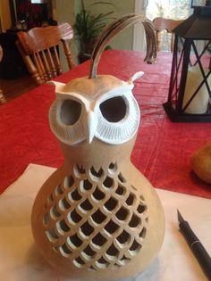 an owl statue sitting on top of a table next to a pen and paper towel