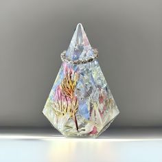 a glass vase with flowers on it sitting on a counter top in front of a gray background