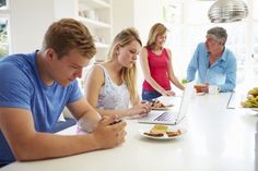 a group of people sitting at a table with food and laptops in front of them