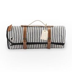 a black and white striped duffel bag with brown leather handles on the handle, sitting on top of a white background