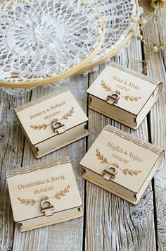 four wooden boxes with wedding rings on them sitting next to a doily and flowers