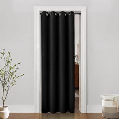 a black curtain hanging on the side of a door in front of a potted plant