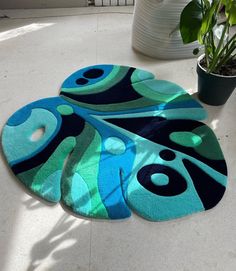 two blue and green rugs sitting on the floor next to a potted plant