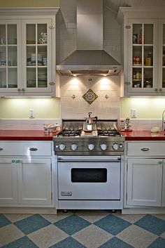 a stove top oven sitting inside of a kitchen next to white cabinets and counter tops