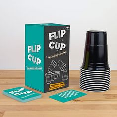 a stack of black cups sitting next to a cardboard box and coasters on top of a wooden table