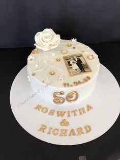 a white cake with gold lettering and a rose on top that says so swithha & richard