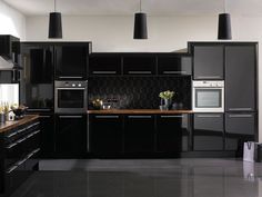 a black and white kitchen with lots of counter space on the side, along with hanging lights