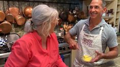 a man and woman in the kitchen preparing food