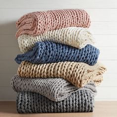 a stack of blankets sitting on top of a wooden floor next to a white wall